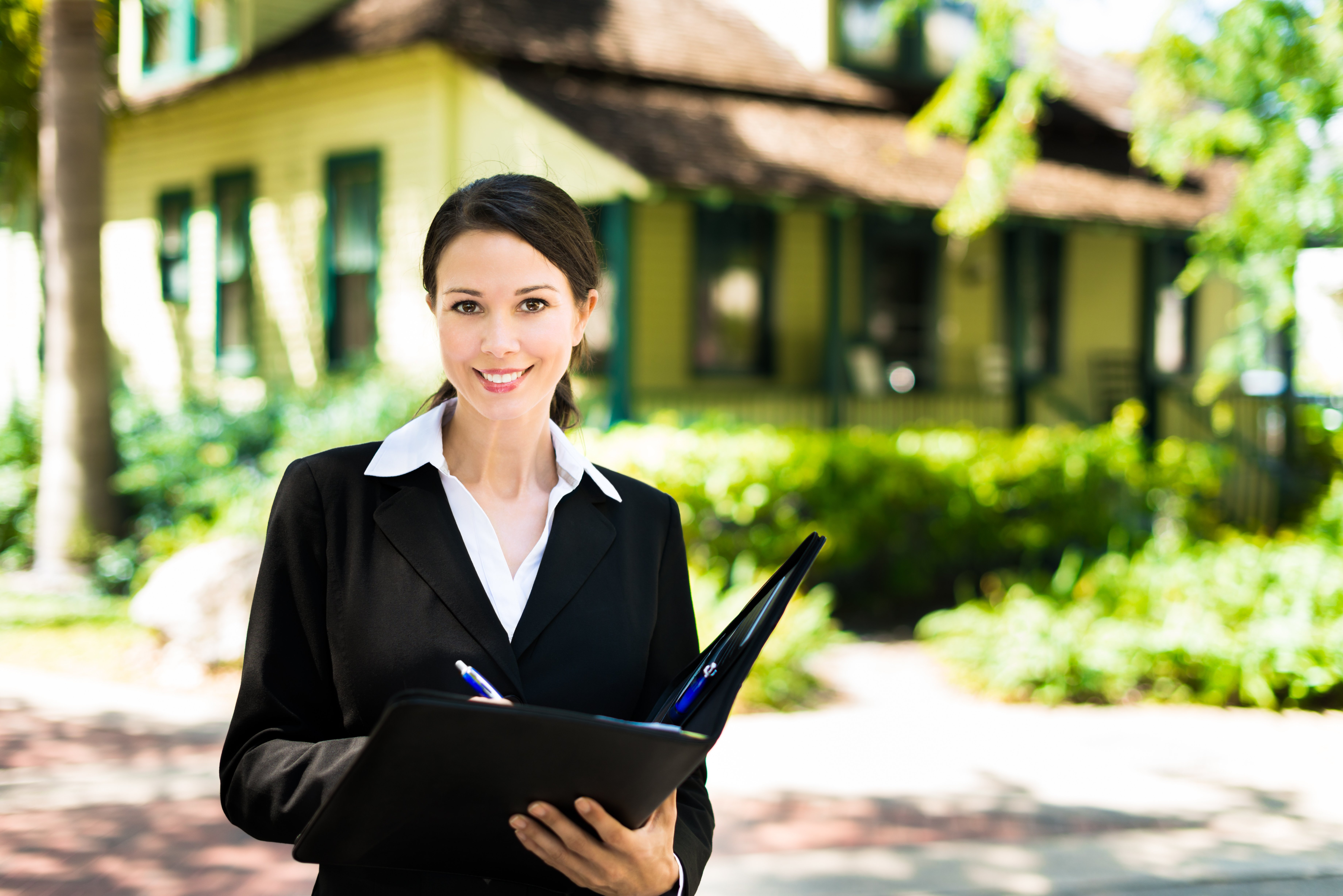 Profession real estate agent standing in front of a bungalow. © Eric Hood / Adobe Stock