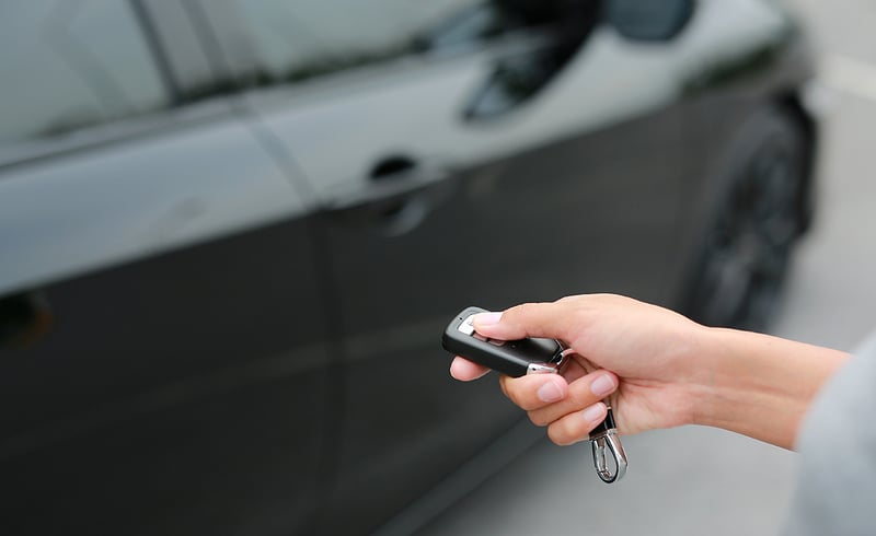A person locking a car with a key fob