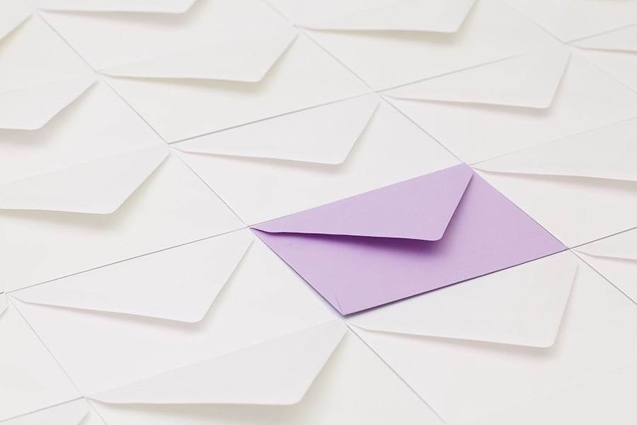 Purple envelop on top of white envelopes