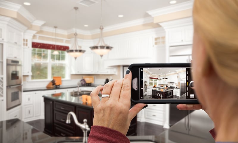 Person taking a photo with a cell phone of a home's kitchen