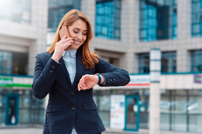 A female professional making a call on her cell phone and checking her watch